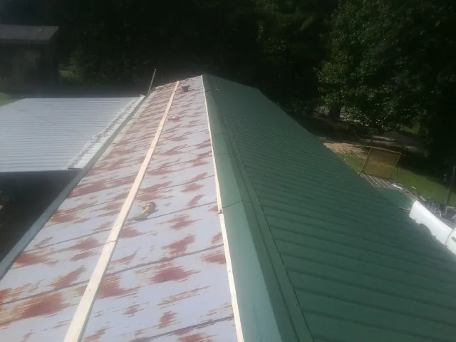 Old rusted panels beside newly installed green metal roofing — Wind Damage Roof Repair by Roofing Brothers in New Lebanon
