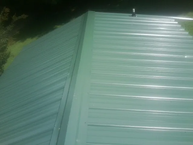 New green metal panels meeting at the ridge of a roof — Flat Roof Repair work by our crew in New Lebanon