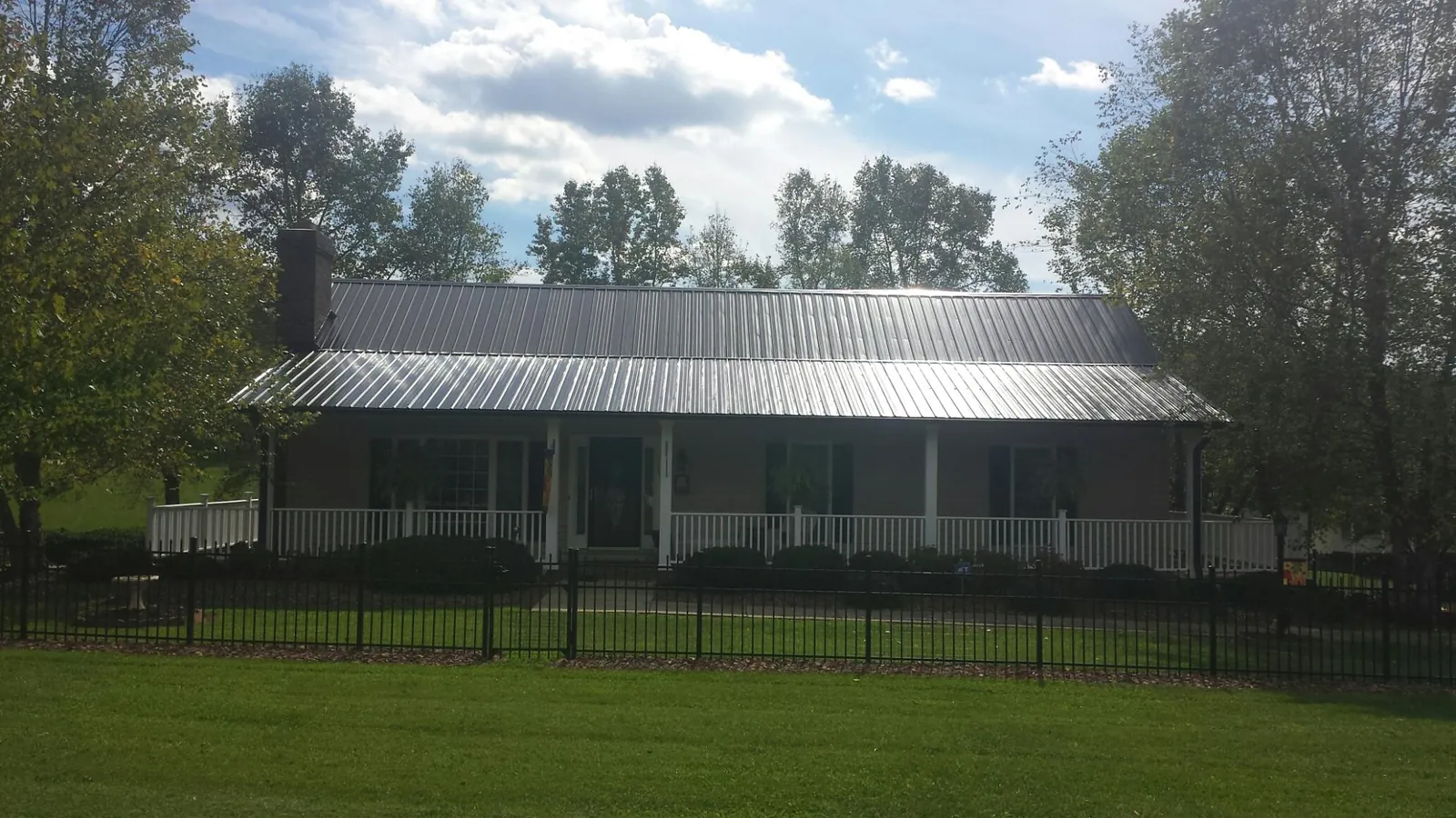 Gray metal roof on a brick ranch with a full width front porch — Gutter Guard Installation work by our crew in New Lebanon
