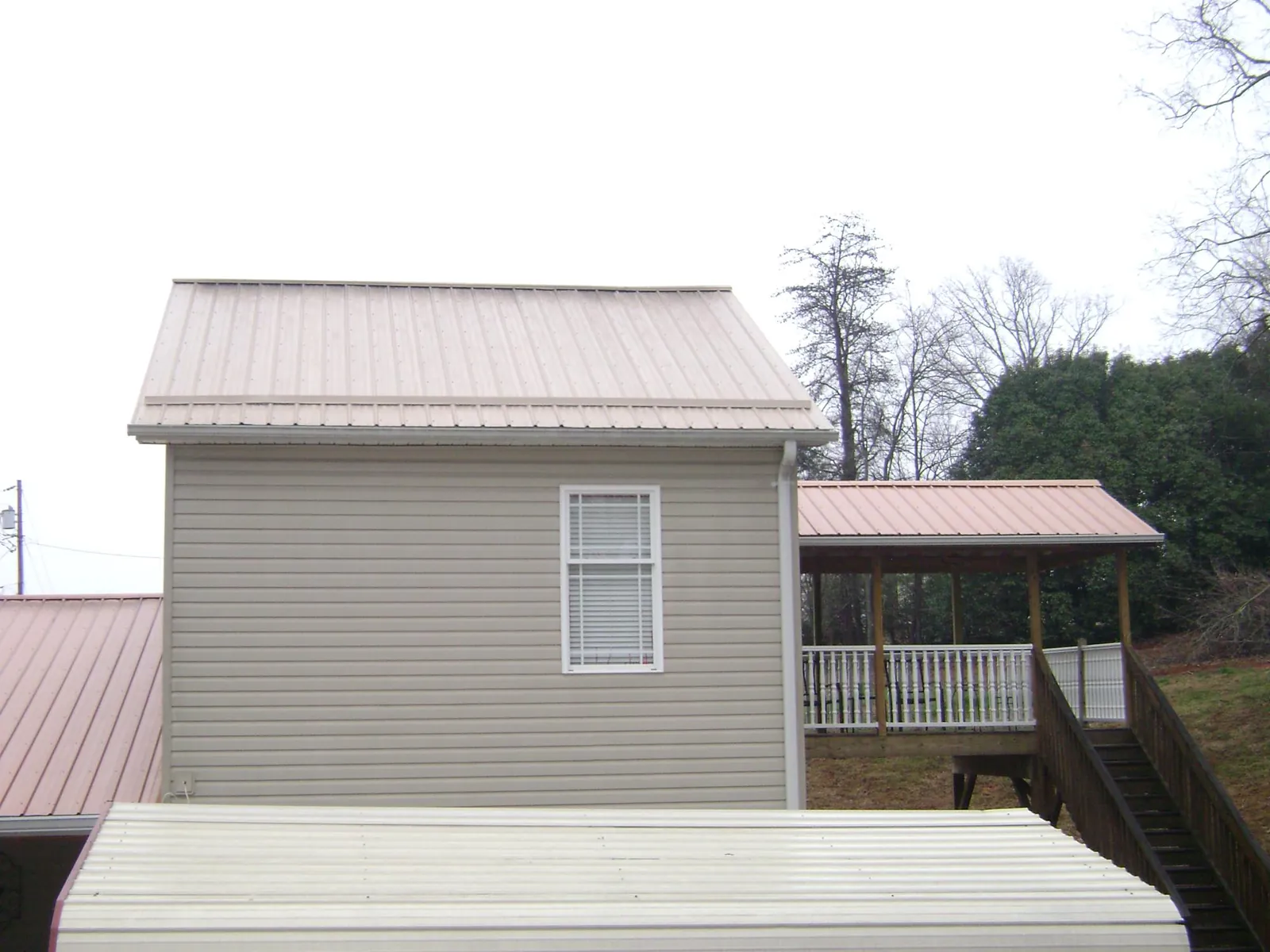 Tan metal roofs on a two story addition and attached porch, from a Roof Replacement job in New Lebanon