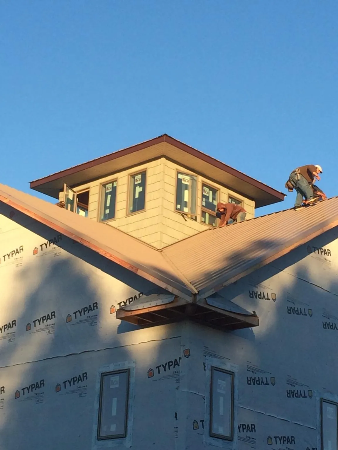 Roofers working around a rooftop cupola on a new metal roof at sunset — Roof Waterproofing in New Lebanon by Roofing Brothers